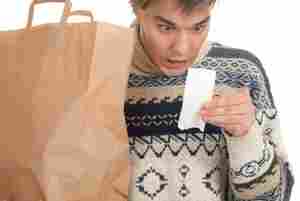 In this file photo, a male model wearing an annoying sweater feigns alarm at a receipt while you fantasize about punching him the face.